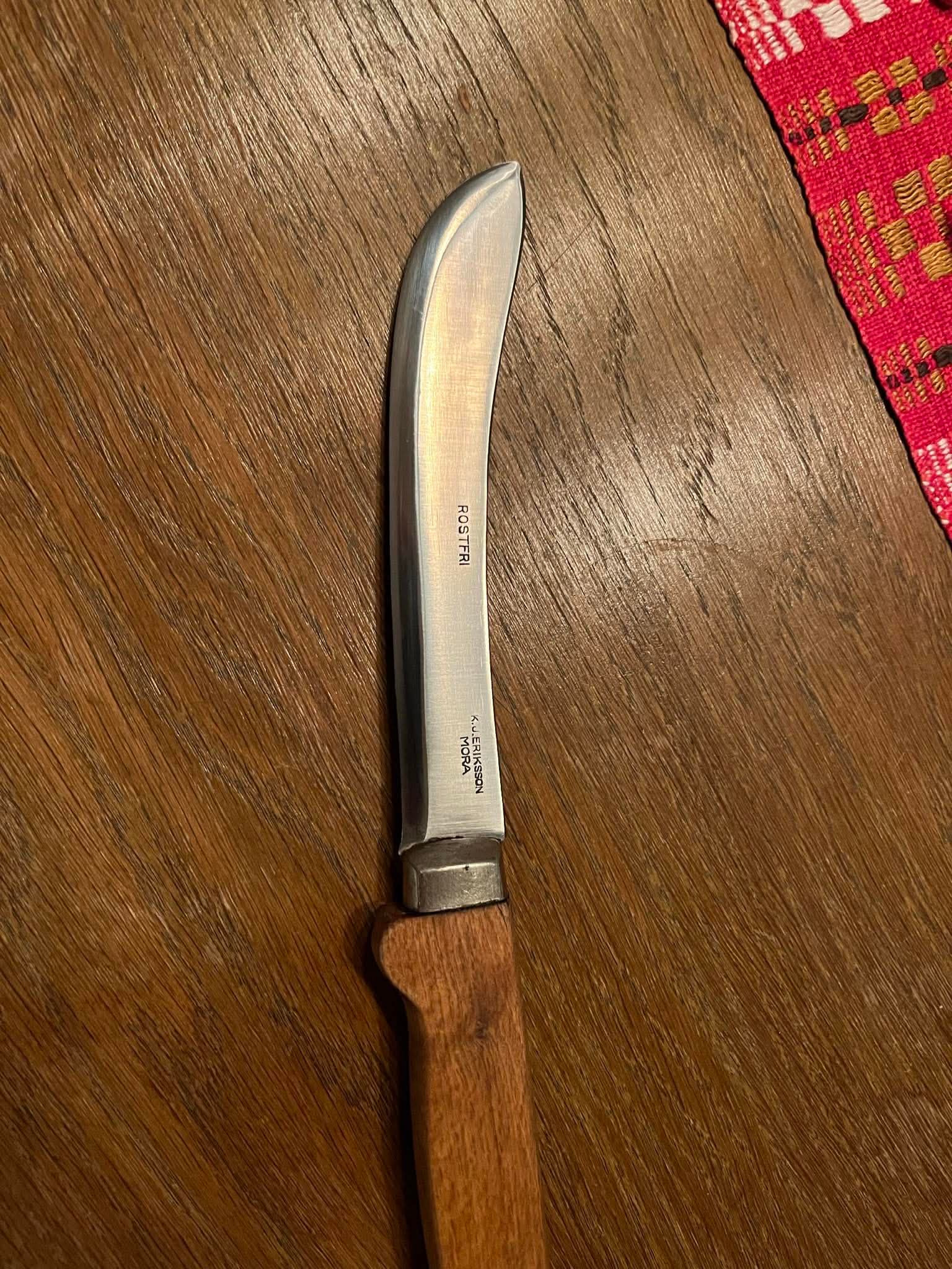 Klassisk tälg-/skärkniv med träskaft på mörkt bord, röd bordsduk i kanten