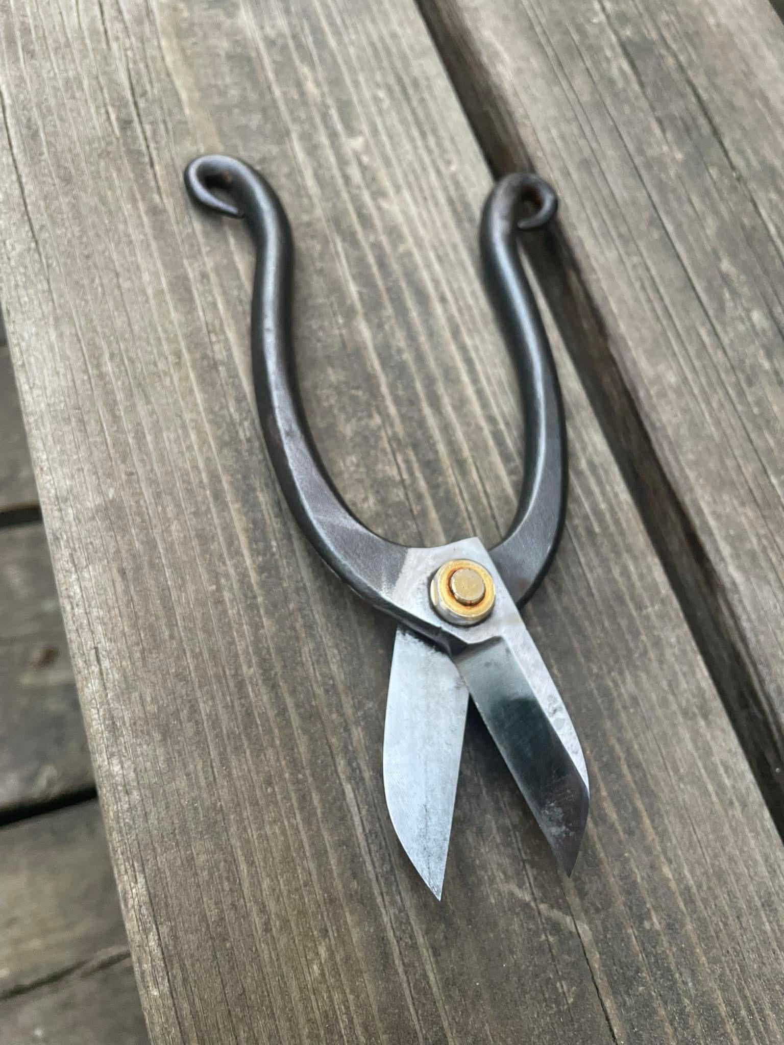 Handsmidd sax med polerade eggar och mörk patina på träbord